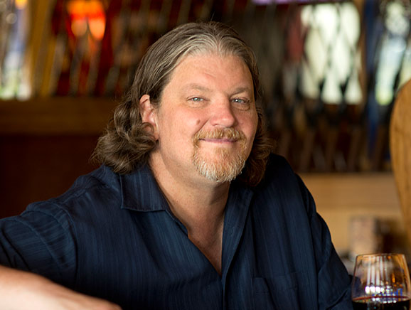 Bill Ranniger holding glass of wine at Duke's